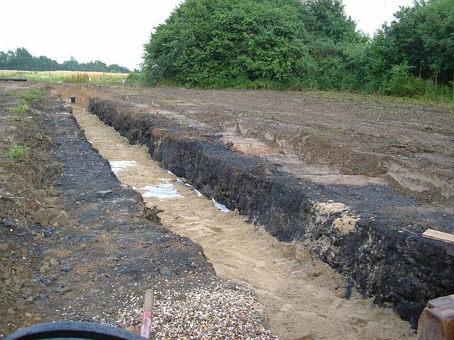 2005_0706_191904.JPG - Mulde vor der Schonung Richtung Osten - Die Rigole  ist mit Sand abgedeckt. Auch hier kann man das Kohlengemisch unbekannten Ursprungs wieder gut erkennen.