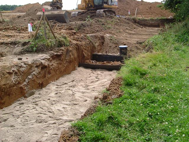 2005_0727_131226.JPG - Bau der Süd-Nord-Rigole hinter dem Altbestand Richtung Süden - im Vordergrund mit Sand abgedeckte Rigole - im Hintergrund Rigolen-Element mit Mutterboden abgedeckt