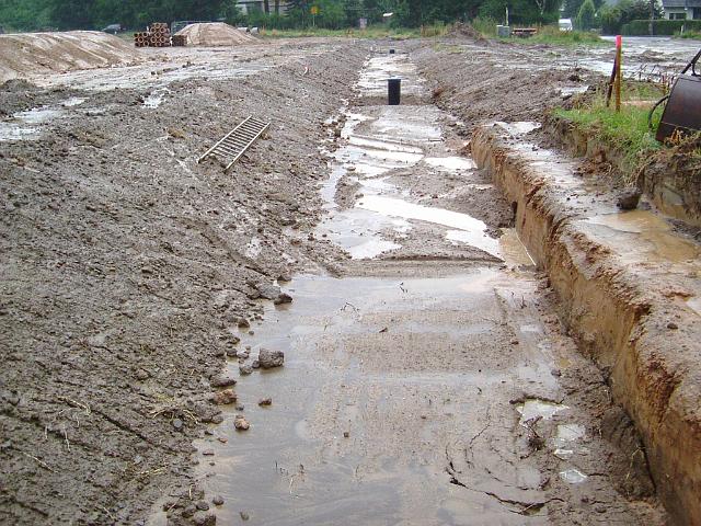 2005_0727_191256.JPG - Mulde im Bau südl. des Altbestandes zwischen Rhönweg und Ewald-Görshop-Straße Richtung Westen - Beim Bau des Mulden-Rohr-Rigolensystems entstanden durch das Ausspülen der Muldenböschungen schon erhebliche Probleme. Diese konnten durch weitere Abschrägung der Böschungen, zu Lasten der Grundstückstiefe, vermindert werden. 